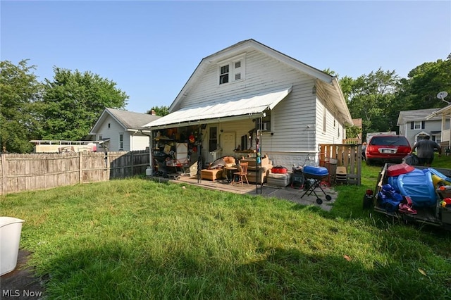 rear view of property with a lawn and fence