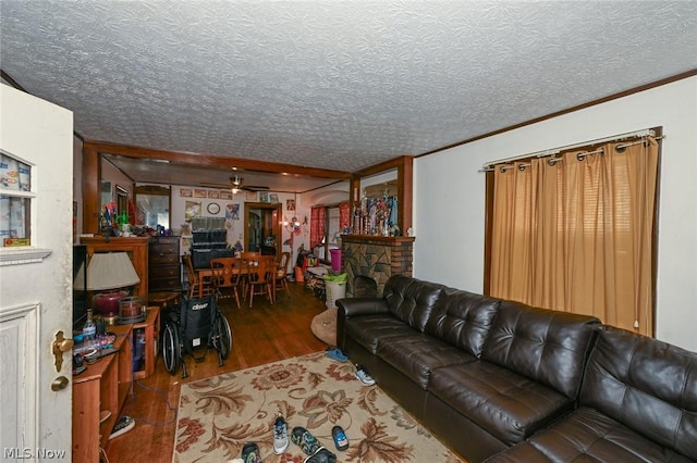 living room with a textured ceiling, a fireplace, wood finished floors, and crown molding