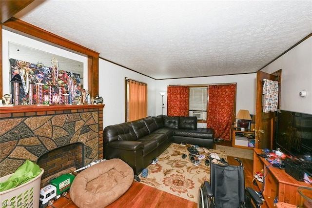 living area with a stone fireplace, crown molding, a textured ceiling, and wood finished floors