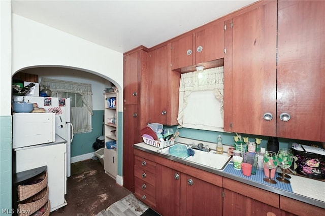 kitchen with baseboards, brown cabinetry, and a sink