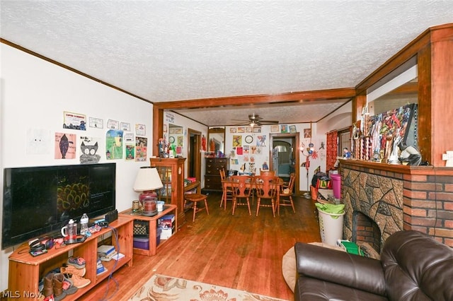 living area featuring ceiling fan, a textured ceiling, a fireplace, and wood finished floors