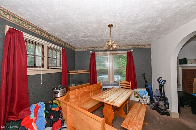 dining room with a textured ceiling, a healthy amount of sunlight, carpet floors, and a notable chandelier