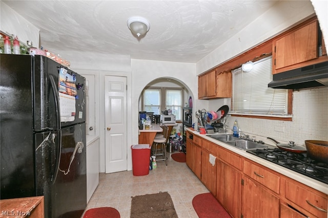 kitchen with decorative backsplash, black refrigerator, sink, and gas cooktop