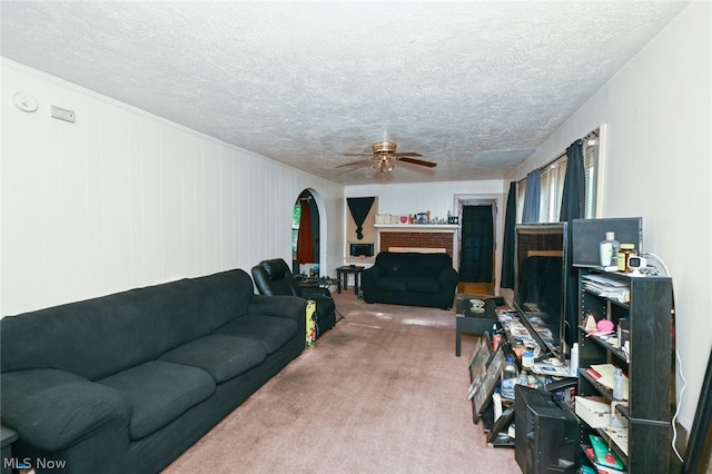 carpeted living room with ceiling fan, a textured ceiling, and a fireplace