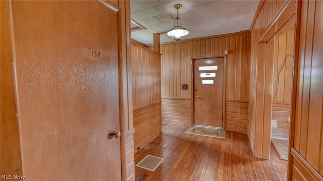 entrance foyer featuring wood-type flooring, ornamental molding, and wooden walls