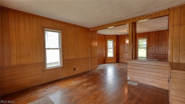 empty room with wood walls and dark wood-type flooring