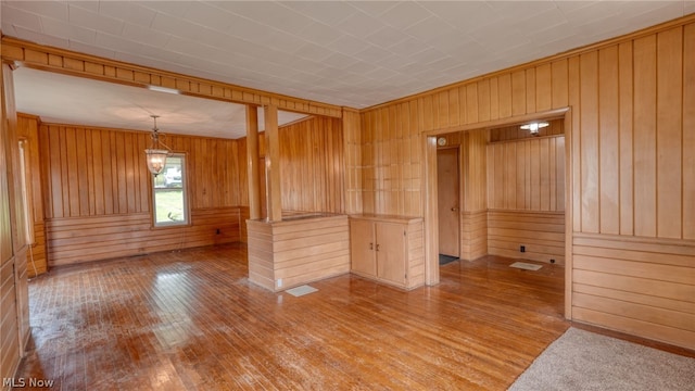 spare room with light hardwood / wood-style floors and wooden walls