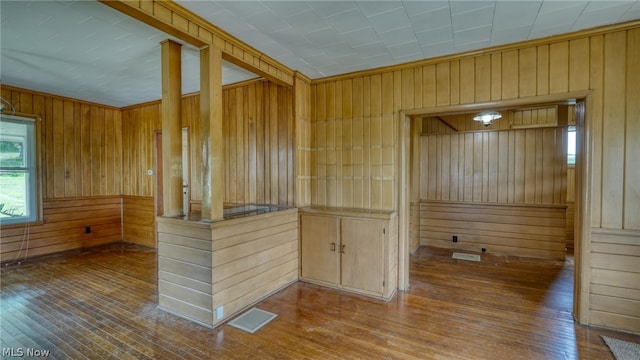 interior space with hardwood / wood-style flooring, wood walls, and light brown cabinets