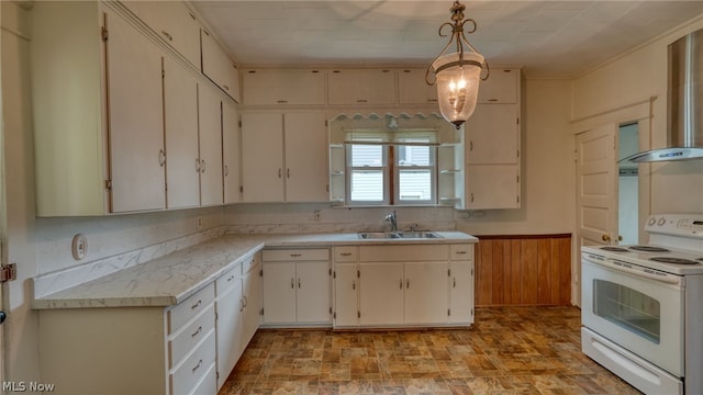 kitchen with hanging light fixtures, sink, white cabinetry, electric stove, and wooden walls