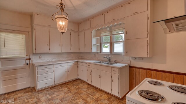 kitchen with white cabinets, white electric stove, wooden walls, sink, and hanging light fixtures