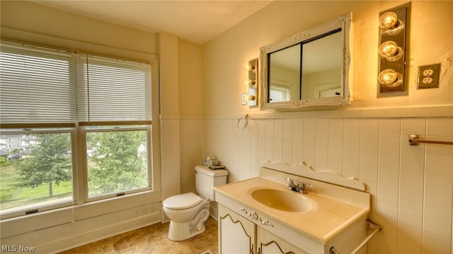 bathroom with toilet, vanity, and tile walls