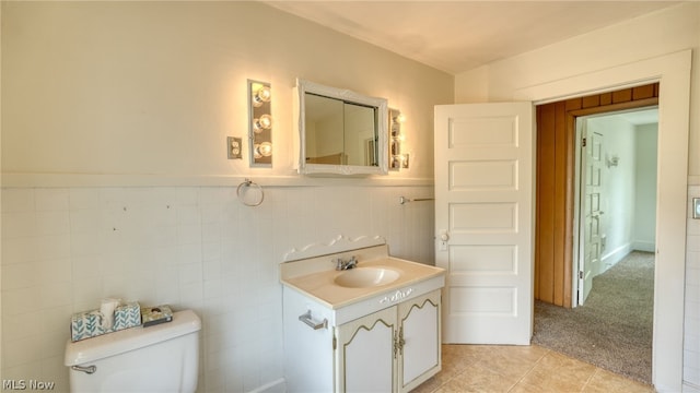 bathroom featuring vanity, toilet, tile walls, and tile patterned flooring