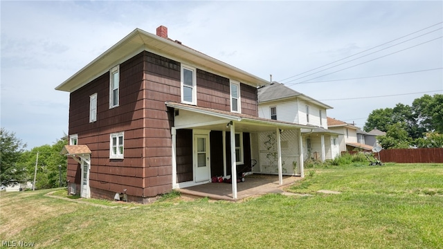 rear view of house featuring a lawn and a patio