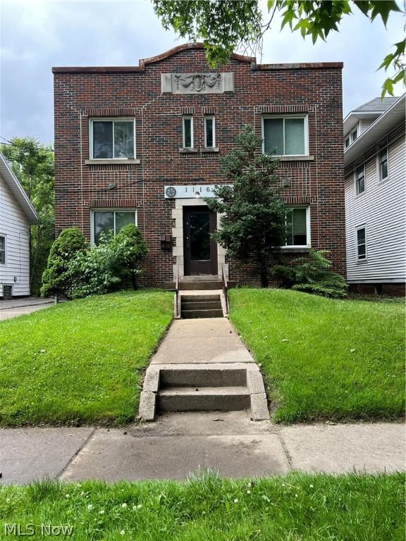 view of front facade with brick siding and a front lawn