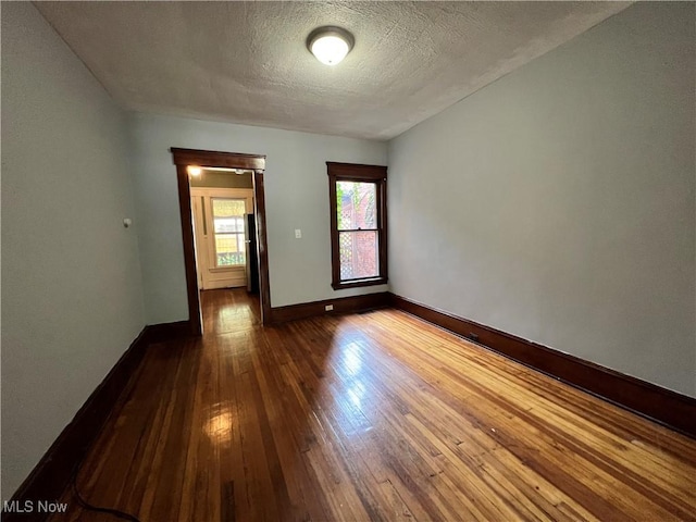 unfurnished room with wood-type flooring and a textured ceiling