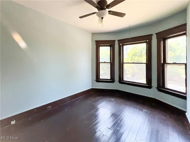 unfurnished room with dark hardwood / wood-style floors, a wealth of natural light, and ceiling fan