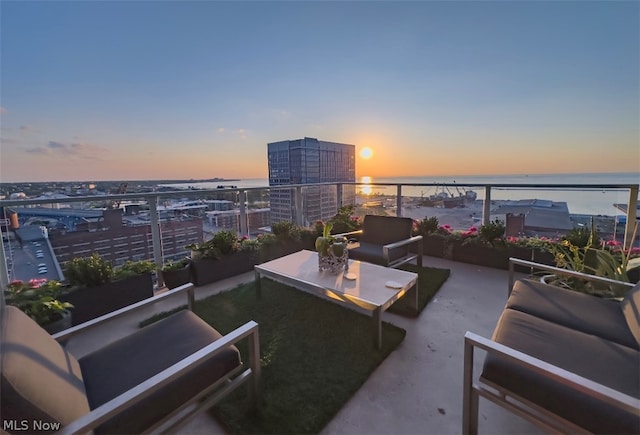 patio terrace at dusk featuring a balcony and a water view