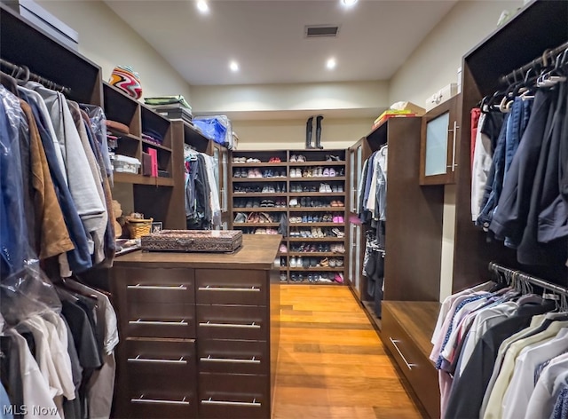 walk in closet with light hardwood / wood-style floors