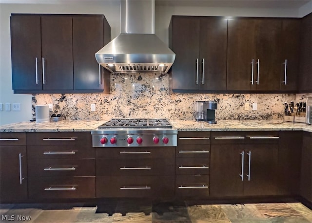 kitchen featuring stainless steel gas cooktop, decorative backsplash, light stone counters, and wall chimney range hood