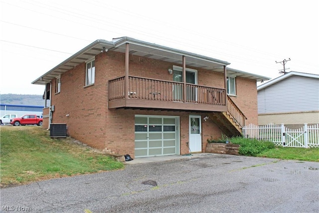 view of front of house featuring brick siding, fence, central AC, and an attached garage