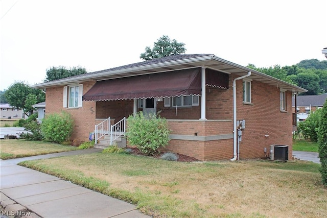 view of front facade featuring central air condition unit, a front yard, and brick siding