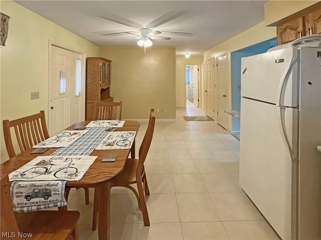 dining area featuring a ceiling fan, baseboards, and light tile patterned floors