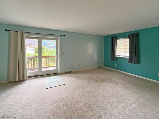 unfurnished room with a healthy amount of sunlight, baseboards, and light colored carpet