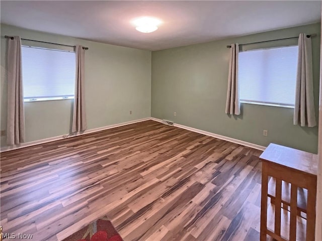 unfurnished room with baseboards, visible vents, and dark wood-style flooring