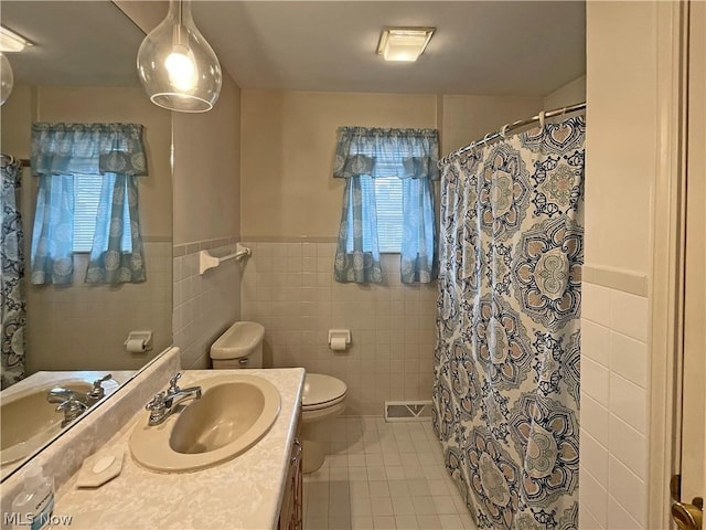 bathroom featuring toilet, a shower with shower curtain, tile walls, vanity, and tile patterned floors