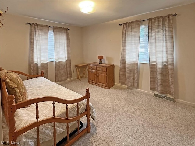 bedroom with light colored carpet, baseboards, and multiple windows