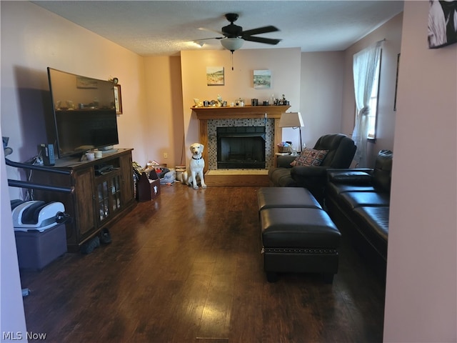 living room with a stone fireplace, dark hardwood / wood-style floors, and ceiling fan