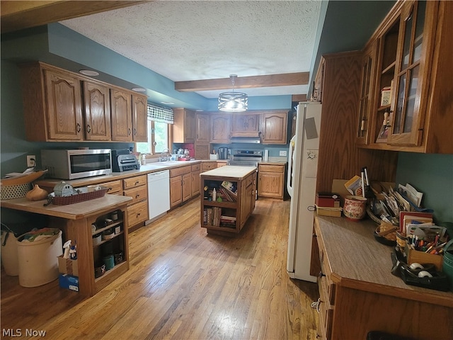 kitchen with white appliances, light wood-type flooring, a textured ceiling, a center island, and hanging light fixtures