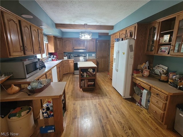 kitchen with appliances with stainless steel finishes, light hardwood / wood-style flooring, sink, decorative light fixtures, and a textured ceiling