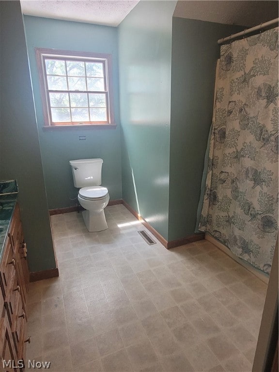 bathroom featuring vanity, toilet, tile patterned floors, and a textured ceiling