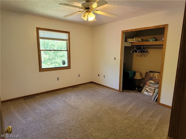 unfurnished bedroom featuring a textured ceiling, carpet, a closet, and ceiling fan