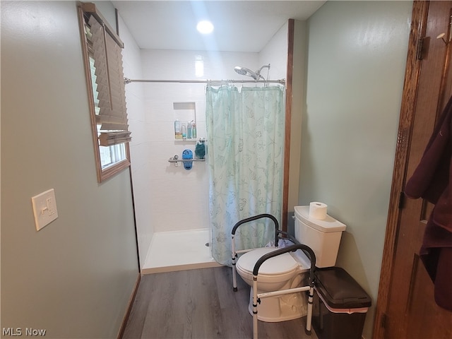 bathroom with hardwood / wood-style flooring, toilet, and curtained shower