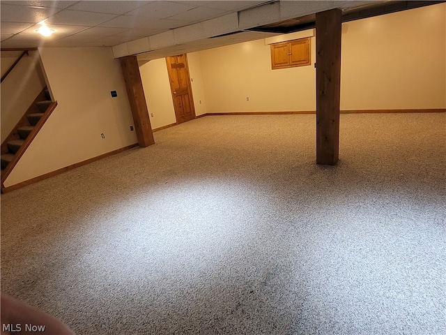 basement featuring a paneled ceiling and light carpet