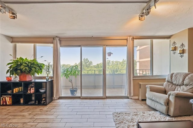 sunroom / solarium featuring rail lighting and radiator heating unit