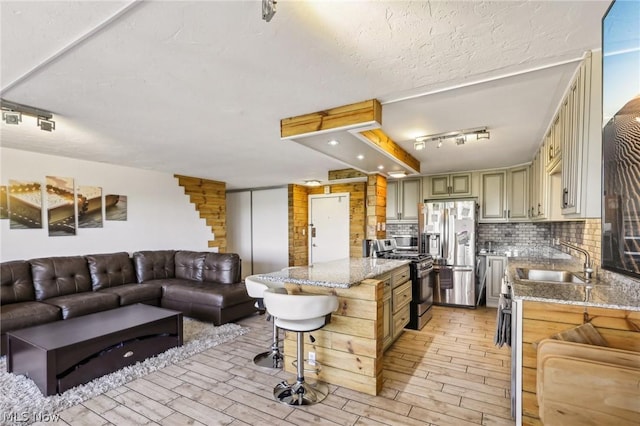 kitchen with sink, light stone counters, green cabinetry, a kitchen breakfast bar, and stainless steel appliances