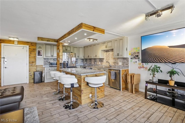 kitchen featuring a breakfast bar area, a center island, appliances with stainless steel finishes, light stone countertops, and backsplash