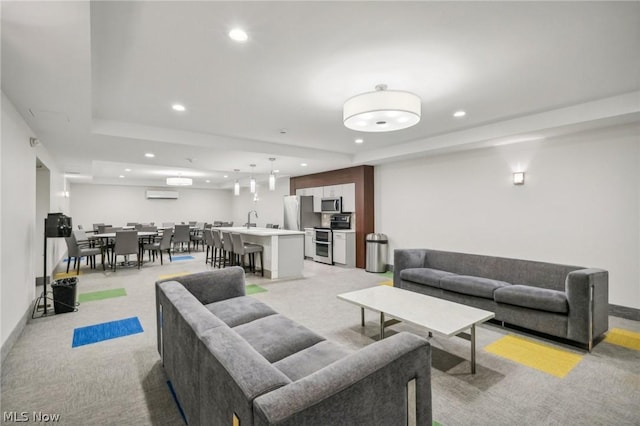 living room featuring a raised ceiling, light carpet, and a wall unit AC