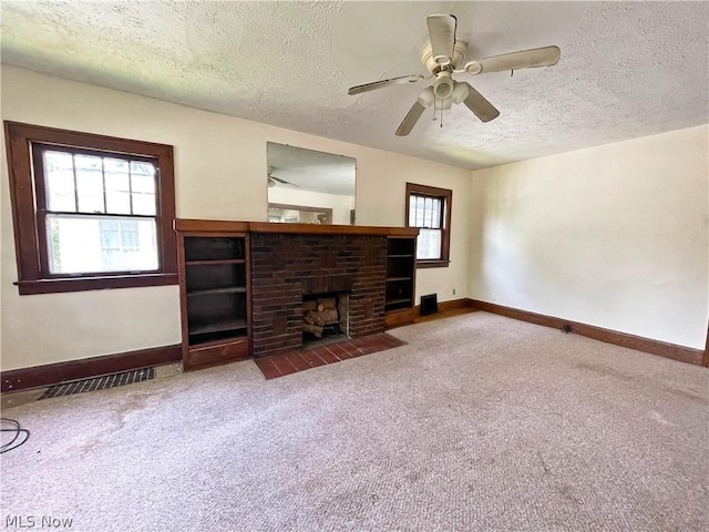 unfurnished living room featuring a textured ceiling, a brick fireplace, and carpet flooring