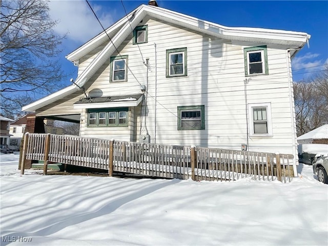 snow covered house with a wooden deck