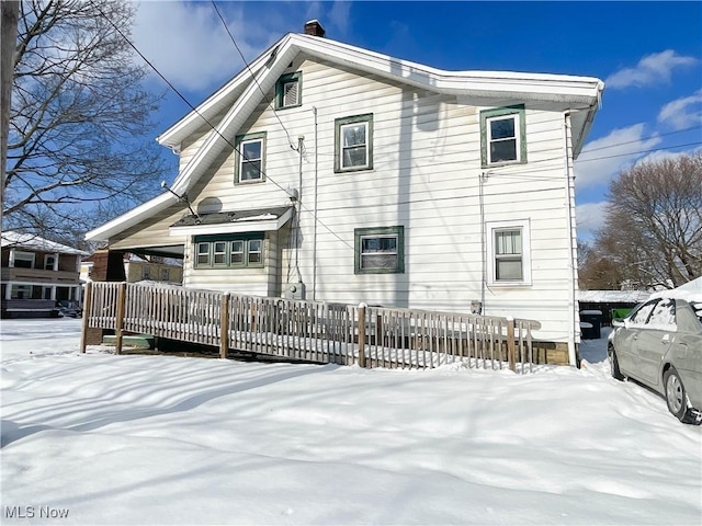 snow covered back of property featuring a deck