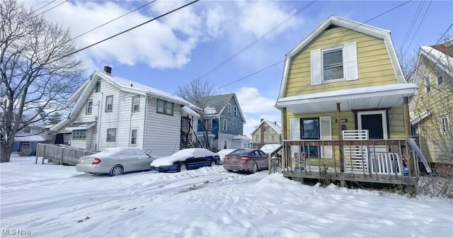 snow covered rear of property with covered porch