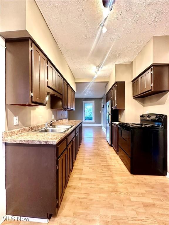 kitchen featuring sink, stainless steel fridge, dark brown cabinets, light hardwood / wood-style floors, and black range with electric cooktop