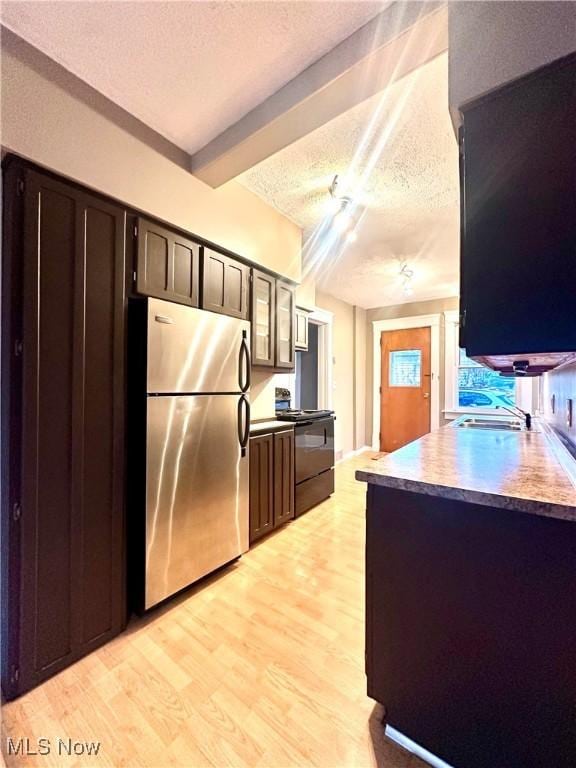 kitchen featuring sink, stainless steel refrigerator, electric range, light hardwood / wood-style floors, and a textured ceiling