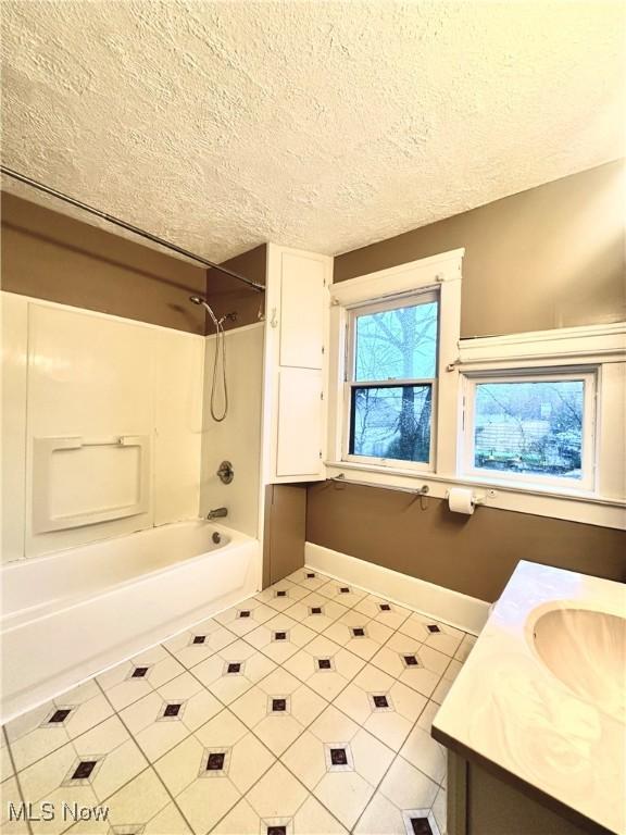 bathroom with tile patterned floors, vanity, tub / shower combination, and a textured ceiling