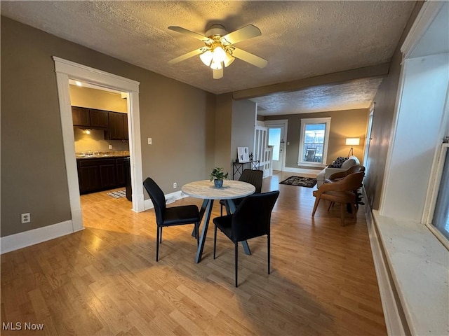 dining room featuring ceiling fan, light hardwood / wood-style flooring, and a textured ceiling