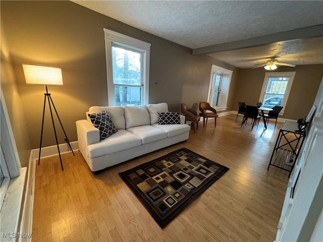 living room featuring ceiling fan, light hardwood / wood-style floors, and a textured ceiling